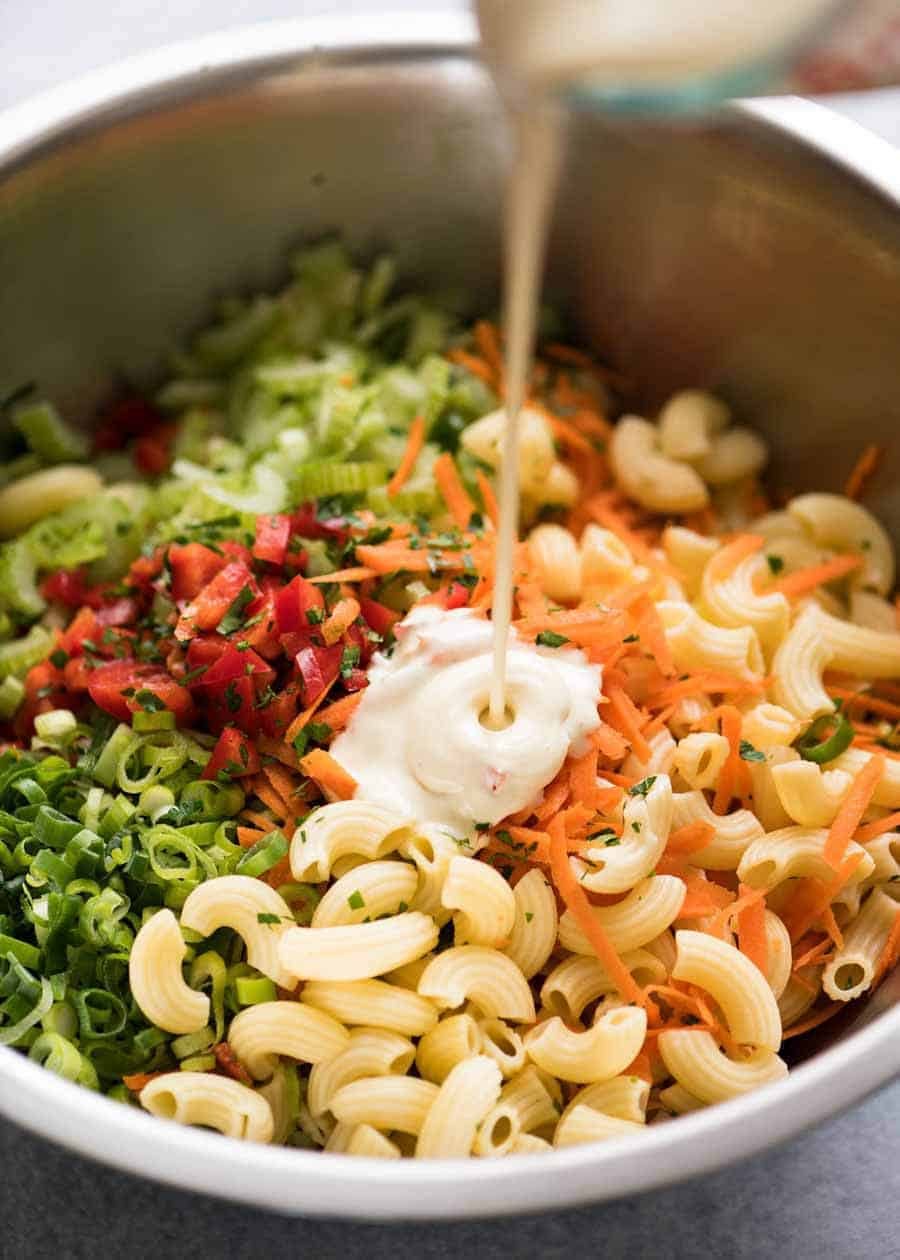 Creamy Macaroni Salad Dressing being poured onto Macaroni Salad