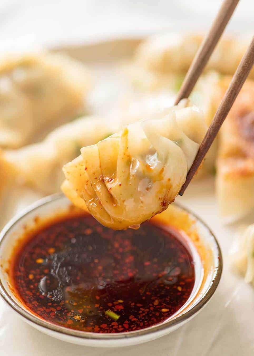 Potsticker being dipped in a small bowl with soy sauce and chilli oil