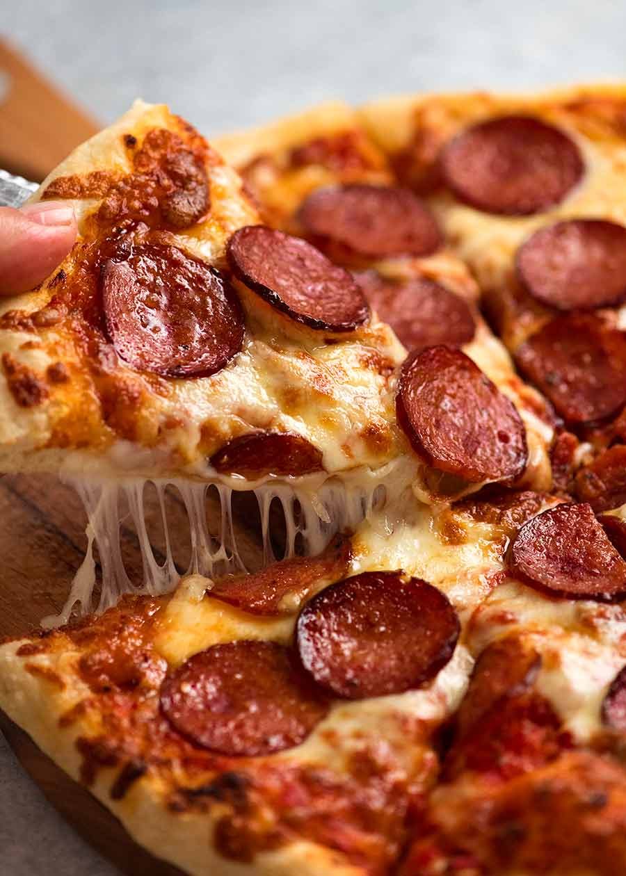 Cheese pull picking up slice of homemade pepperoni pizza