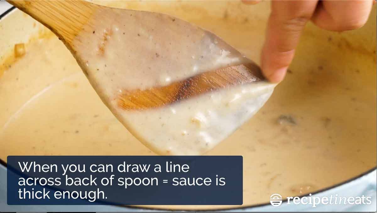Drawing a line across the spoon to check thickness of béchamel sauce